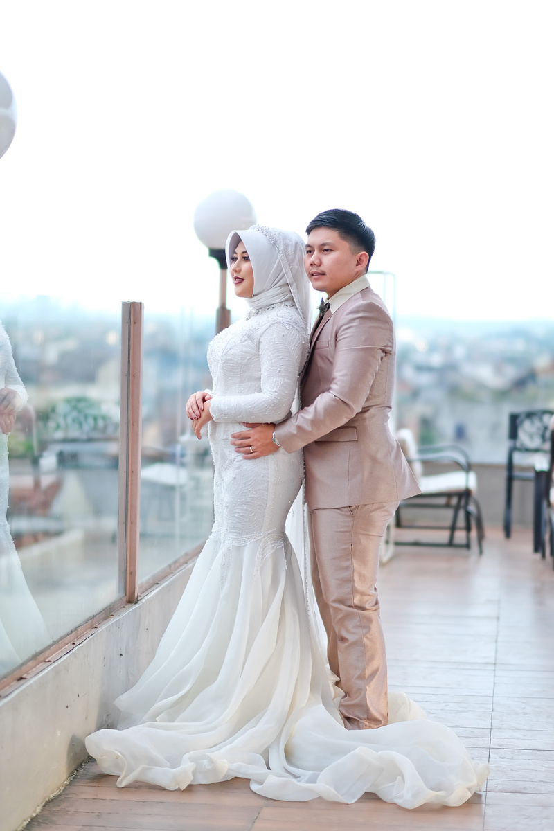 Young Asian just married couple enjoying cityscape standing on balcony of big building